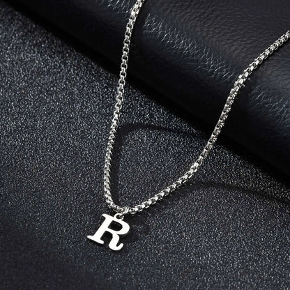 Silver necklace with a 'R' pendant on a black textured surface