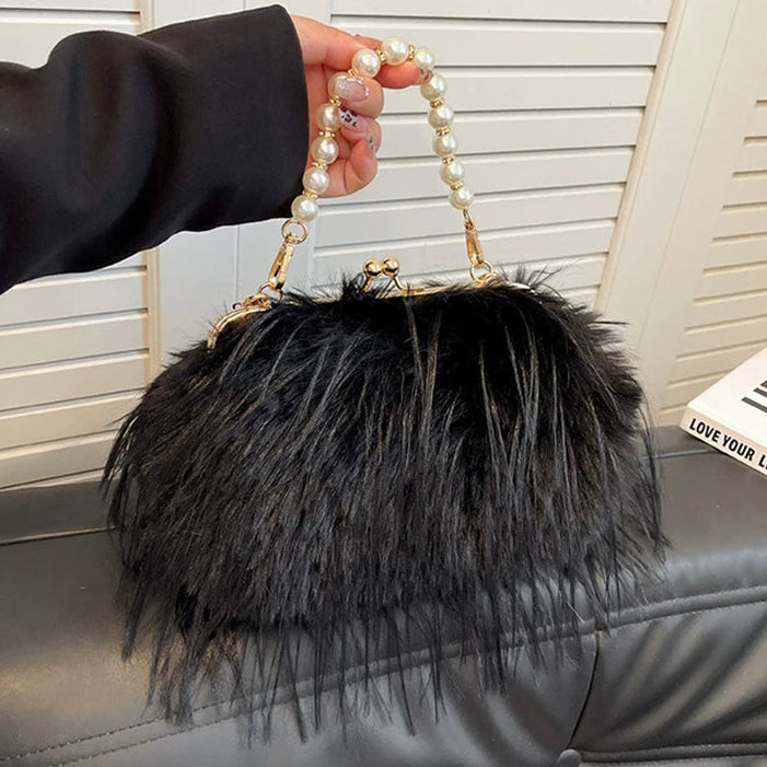 Black fluffy handbag with pearl handle held by a person against a neutral background