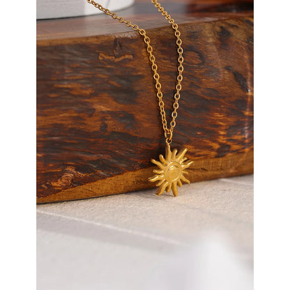Gold sun-shaped pendant necklace on a wooden surface