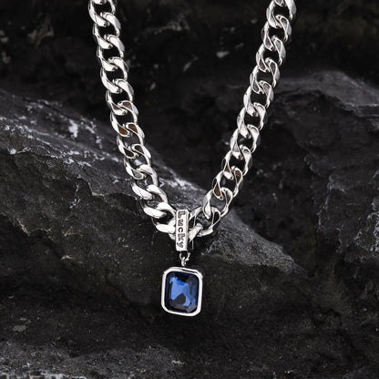 Silver chain necklace with a blue pendant on a dark stone surface
