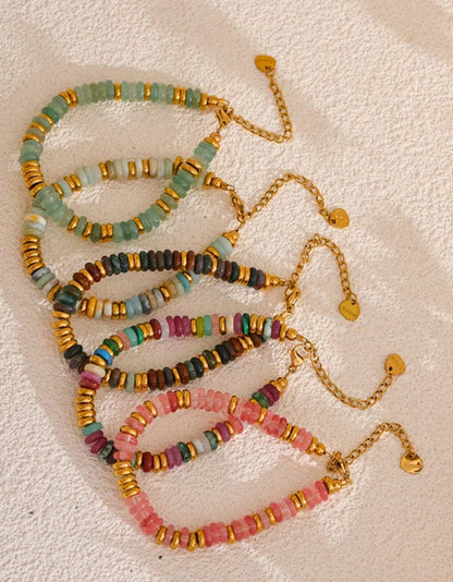 Colourful beaded necklaces and bracelets on a textured surface.