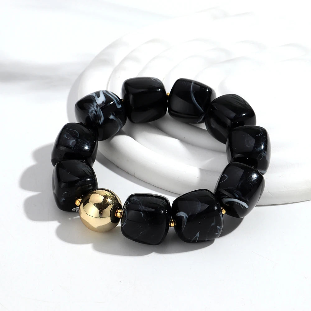 Black beaded bracelet with a gold bead on a white background