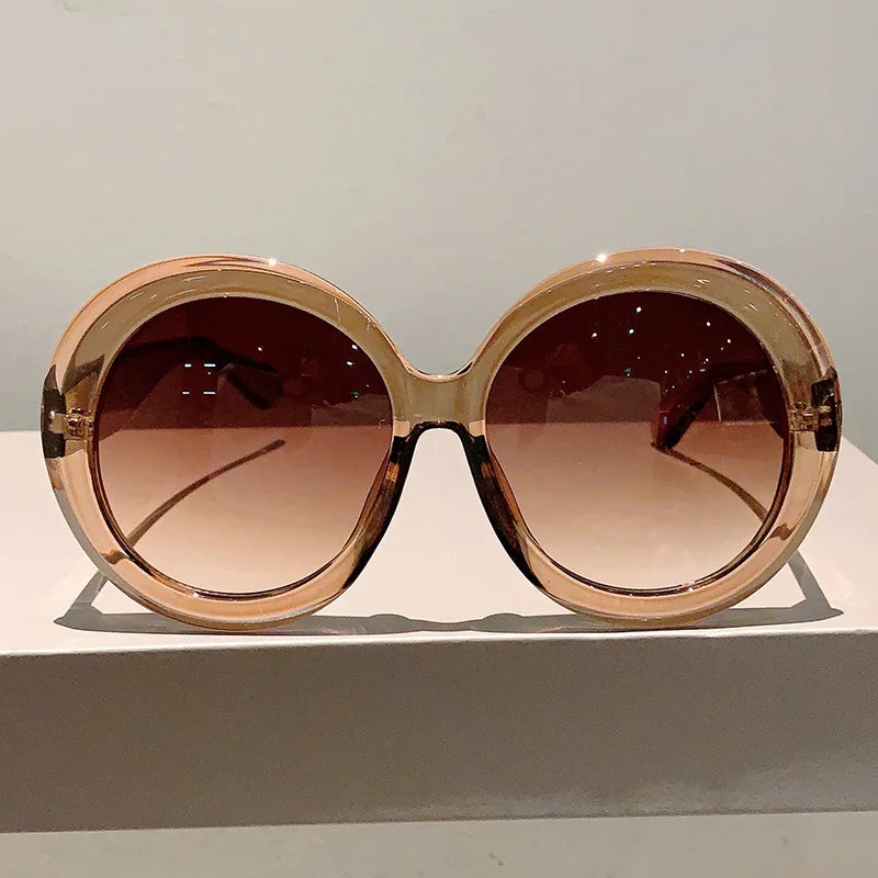 Large round sunglasses with a rose gold frame on a light gray background