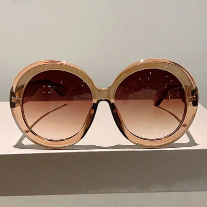 Large round sunglasses with a rose gold frame on a light gray background