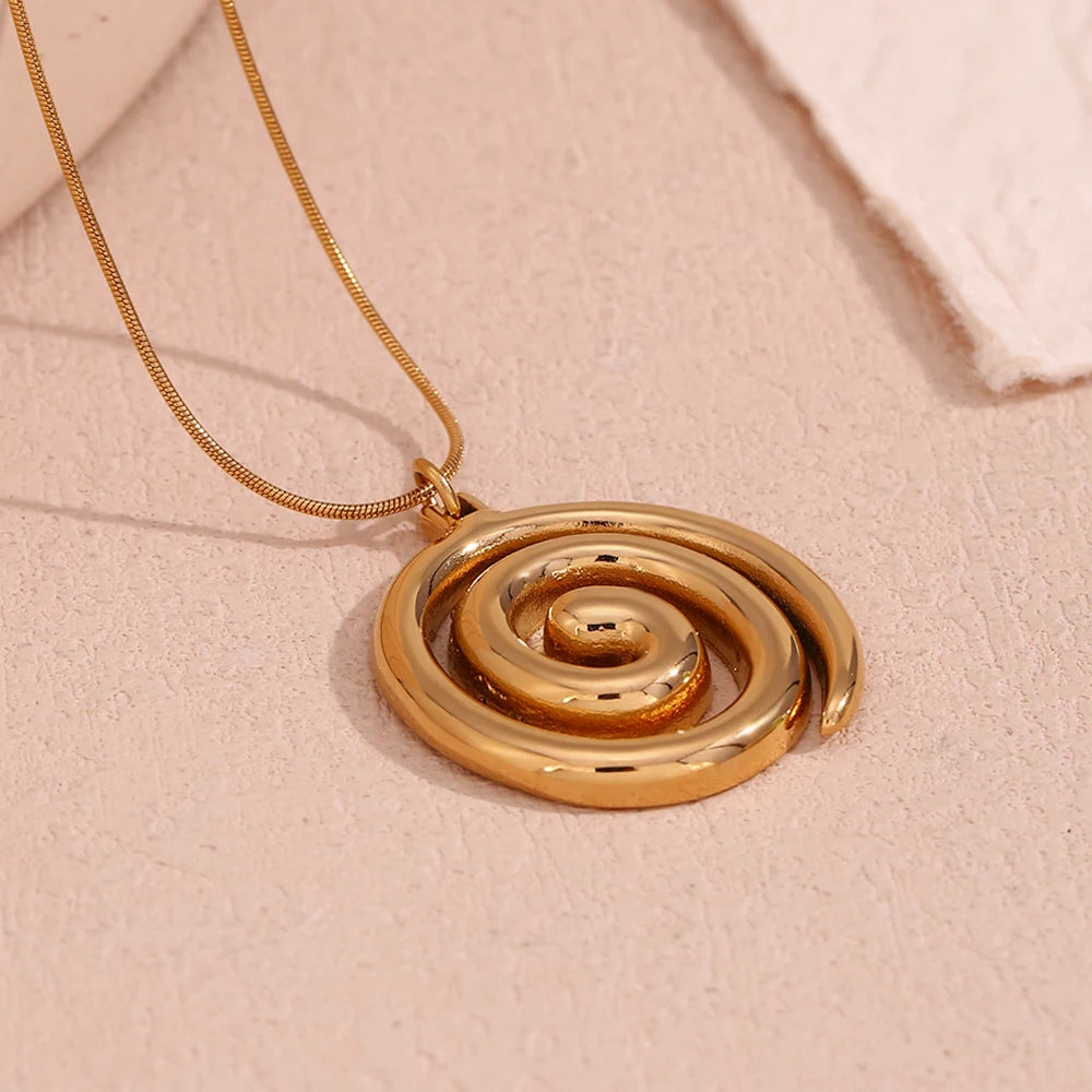 Gold spiral pendant necklace on a beige background