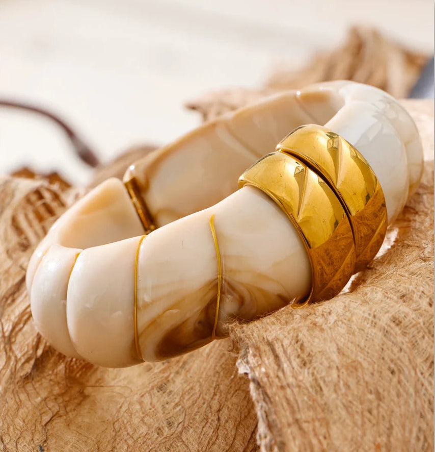 Marbled white bracelet on a textured beige surface.