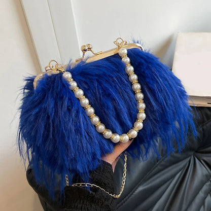 Blue feathered handbag with pearl chain held by a person against a neutral background