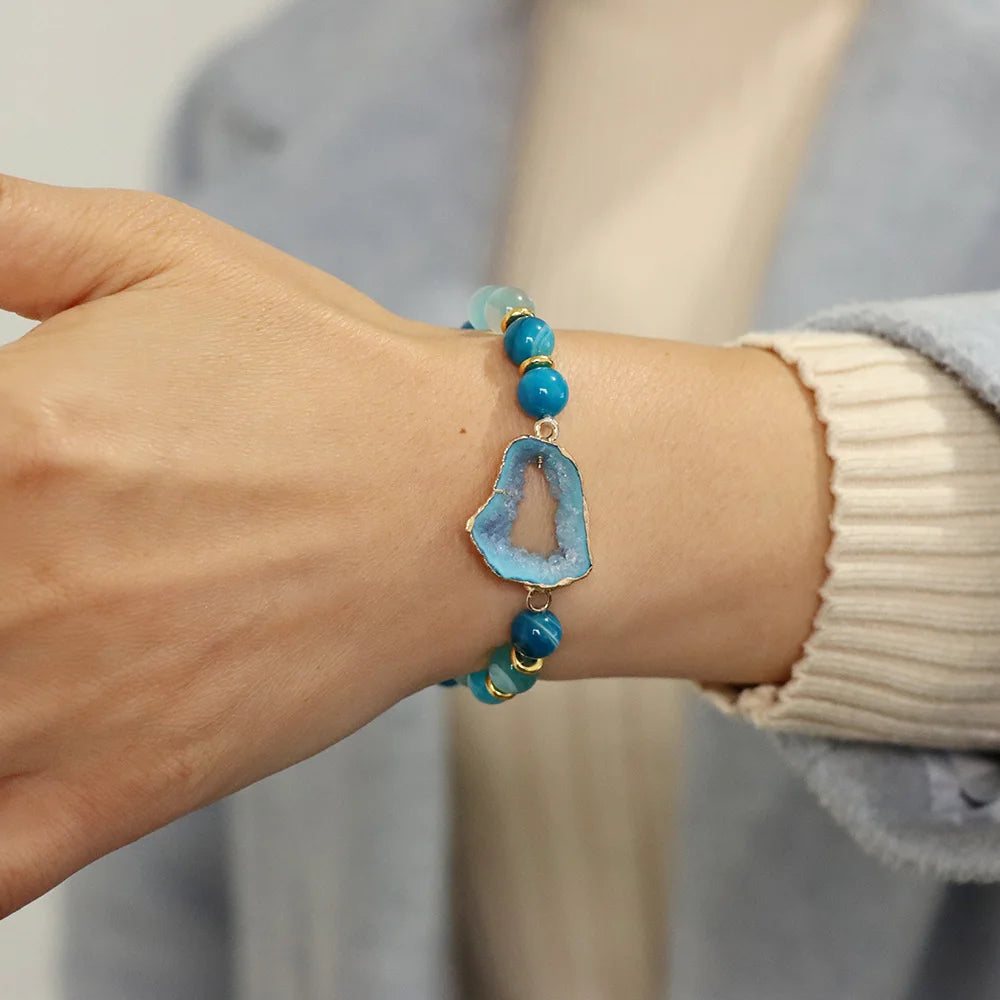 Bracelet with blue agate stone and beads on a wrist against a neutral background