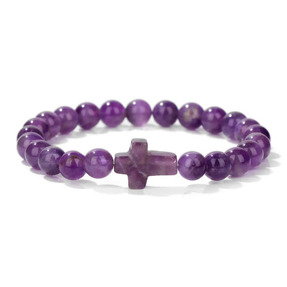 Purple beaded bracelet with a cross charm on a white background
