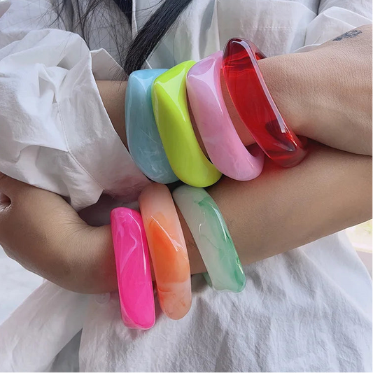 Colourful bangles on a person's wrist with a white shirt background