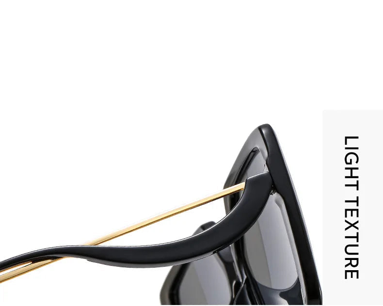Close-up detail shot of black sunglasses with gold metal temples and dark tinted lenses.
