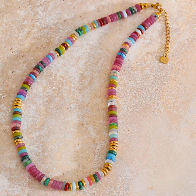 Colourful beaded necklace on a textured beige surface.