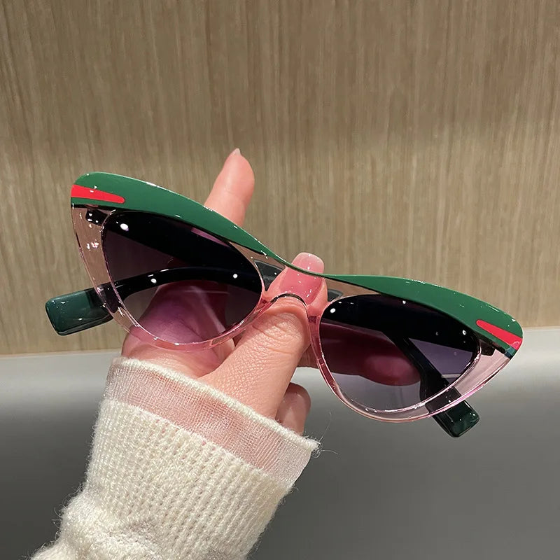 Sunglasses with green and red accents held by a hand against a neutral background