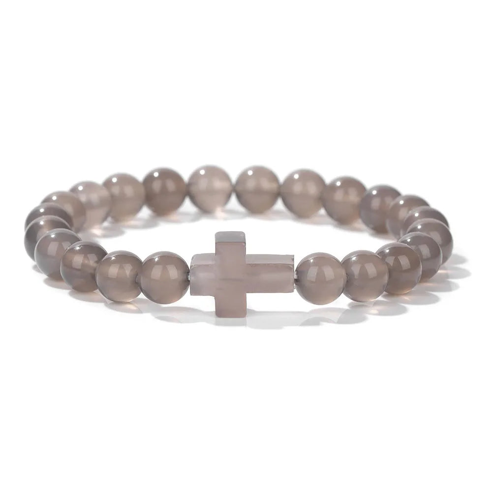 Bracelet with gray beads and a cross charm on a white background
