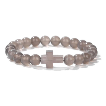 Bracelet with gray beads and a cross charm on a white background