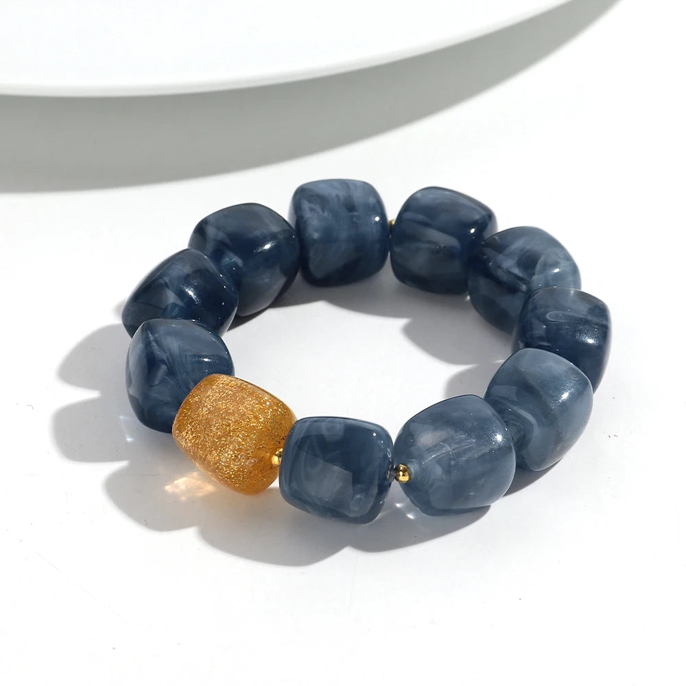 Blue beaded bracelet with a gold accent on a white background