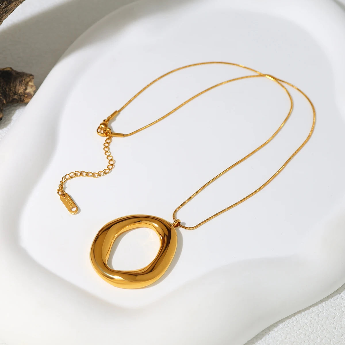 Gold necklace with a unique pendant on a white surface