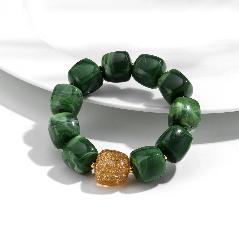 Green beaded bracelet with a gold accent on a white background