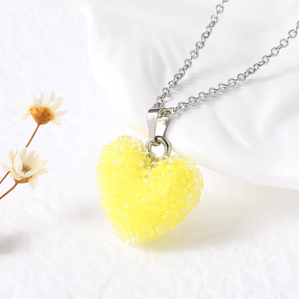 Yellow heart-shaped pendant on a chain with dried flowers on a white background
