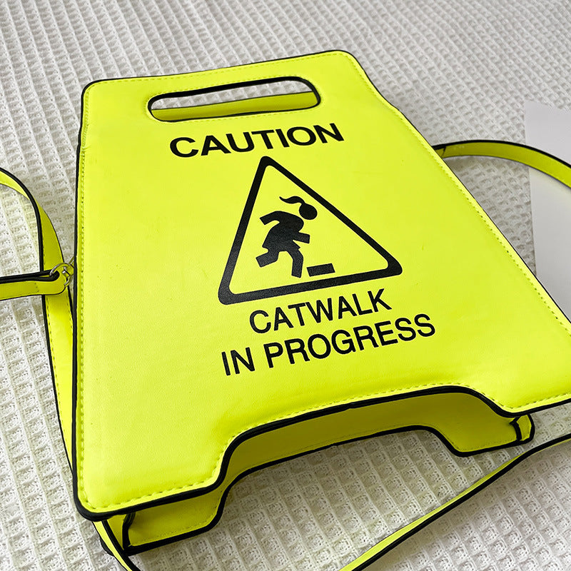 Yellow sign with 'Caution: Catwalk in Progress' text and symbol on a textured surface