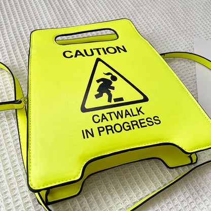 Yellow sign with 'Caution: Catwalk in Progress' text and symbol on a textured surface