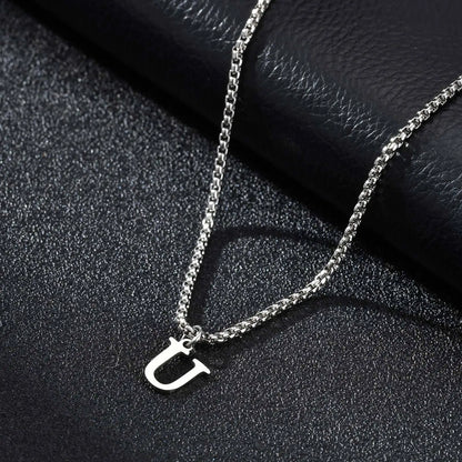 Silver necklace with a 'U' pendant on a black textured surface