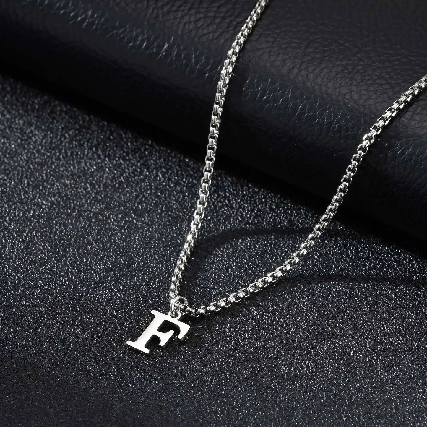 Silver necklace with a 'F' pendant on a dark textured surface