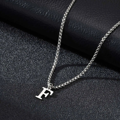 Silver necklace with a 'F' pendant on a dark textured surface