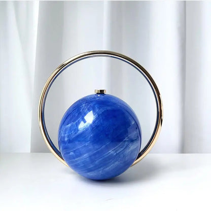 Blue spherical clutch bag with a gold circular frame on a white background