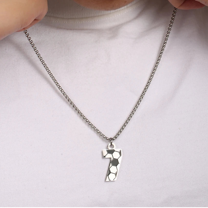 Person wearing a necklace with a unique pendant on a plain background