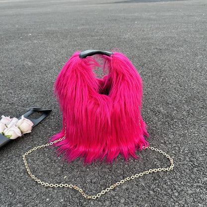 Pink furry handbag with a chain strap on a gray surface
