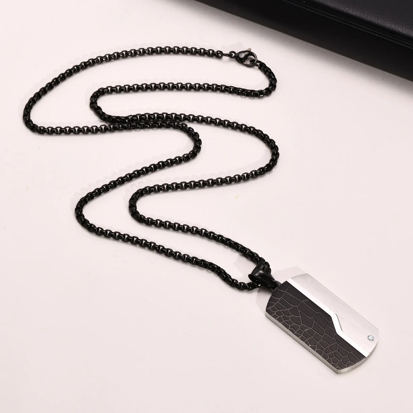 Black beaded necklace with a rectangular pendant on a white background