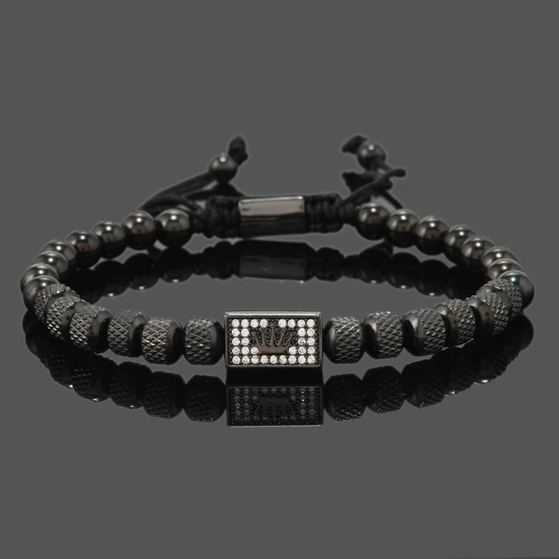 Black beaded bracelet with a square charm on a reflective surface