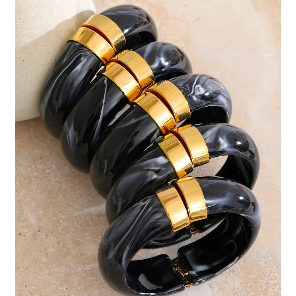 Black and gold bracelet on a beige stone surface