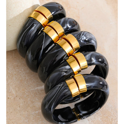 Black and gold bracelet on a beige stone surface