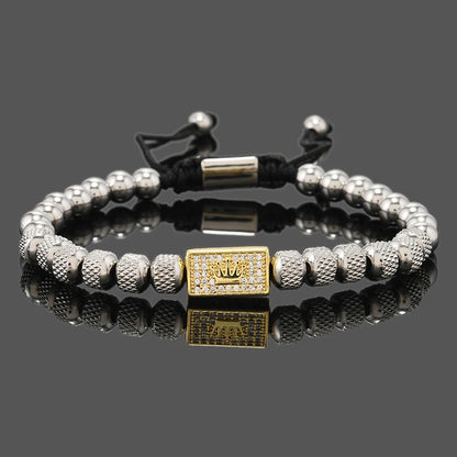 Bracelet with silver beads and a gold charm on a reflective surface