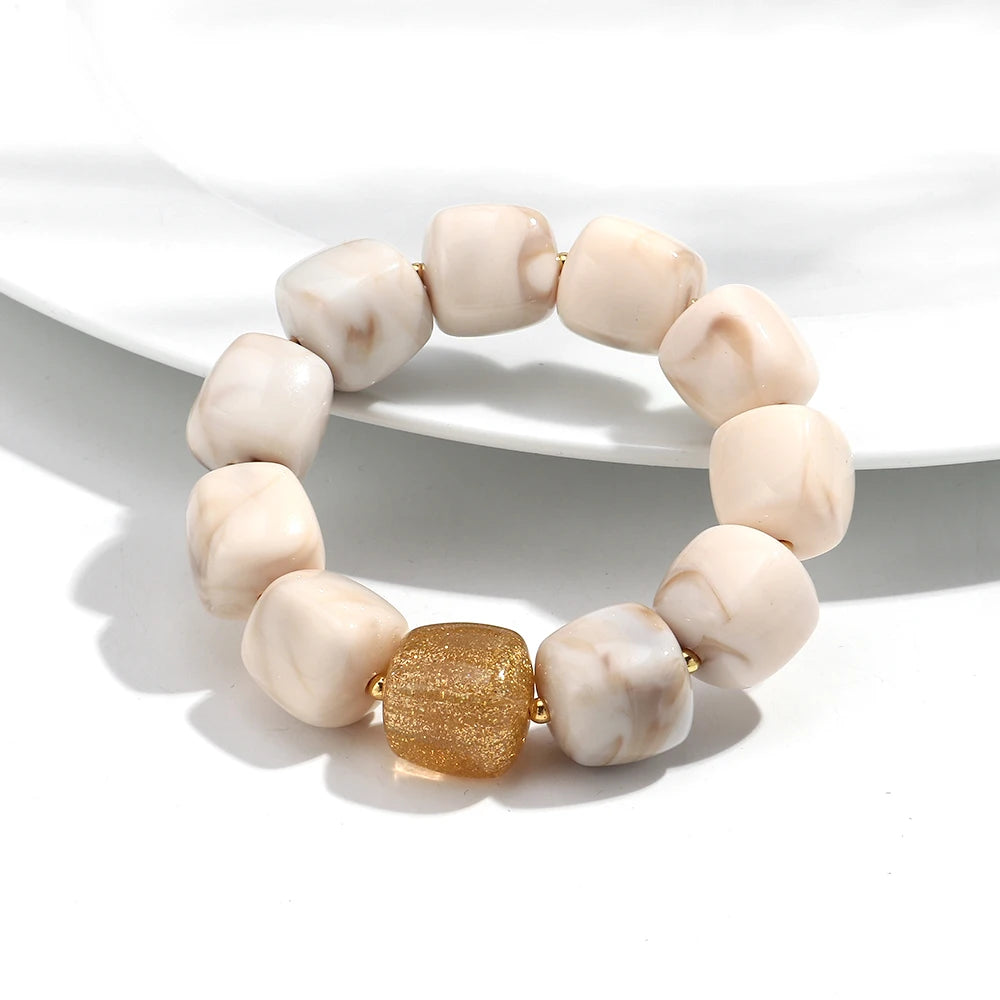 Beige stone bracelet with a gold bead on a white background