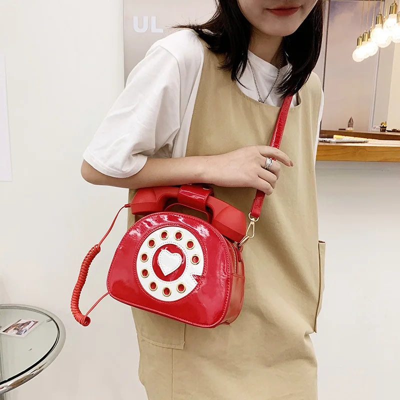 Person holding a red phone-shaped handbag with a white background
