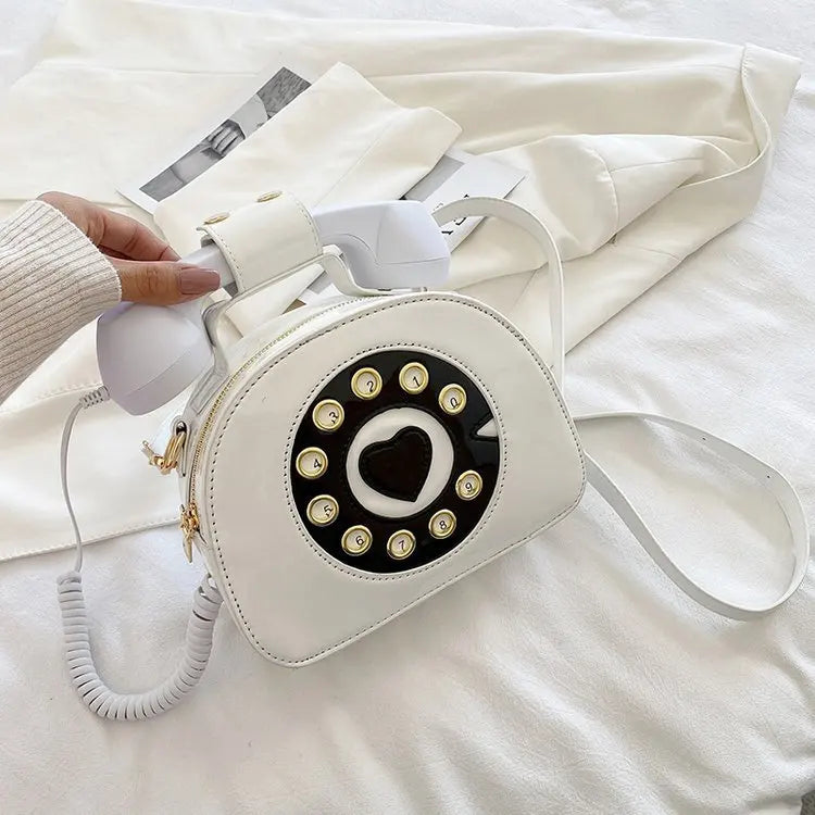 White phone-shaped handbag with black heart design on a white surface