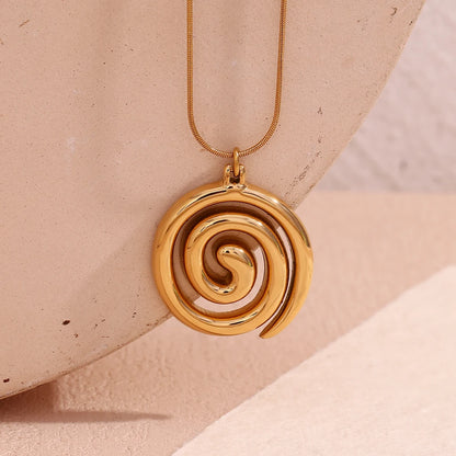 Gold spiral pendant necklace on a beige background