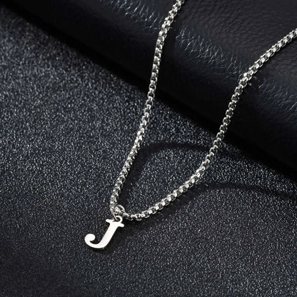 Silver necklace with a 'J' pendant on a dark textured surface
