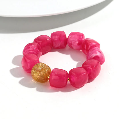Pink beaded bracelet with a gold bead on a white background