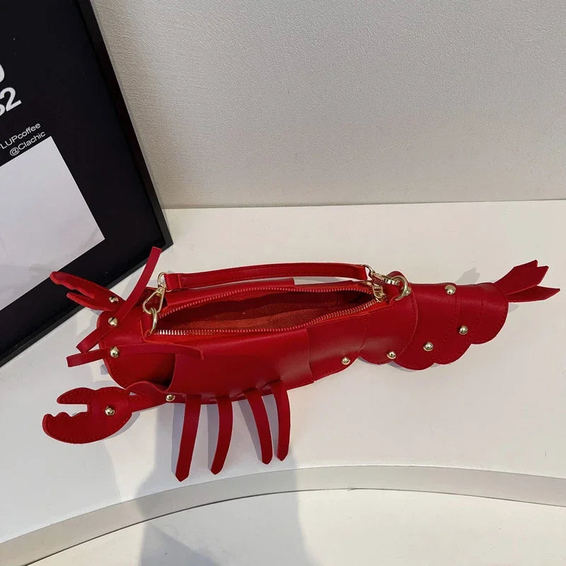 Red lobster-shaped handbag on a white surface with a black frame in the background.