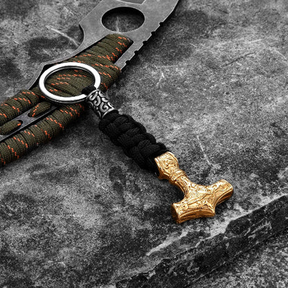 Keychain with gold Thor's hammer charm on a dark stone surface