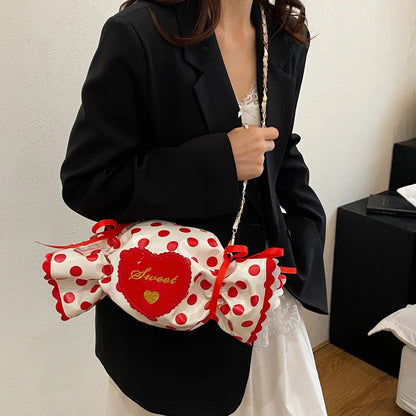 Person holding a polka dot bag with a red bow in a room setting.