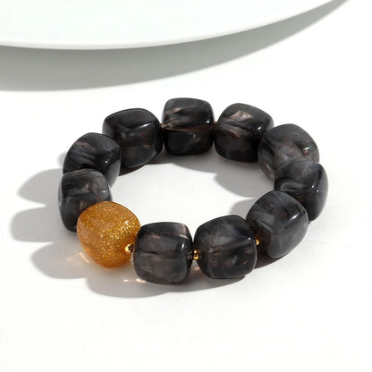 Bracelet with dark beads and a gold bead on a white background