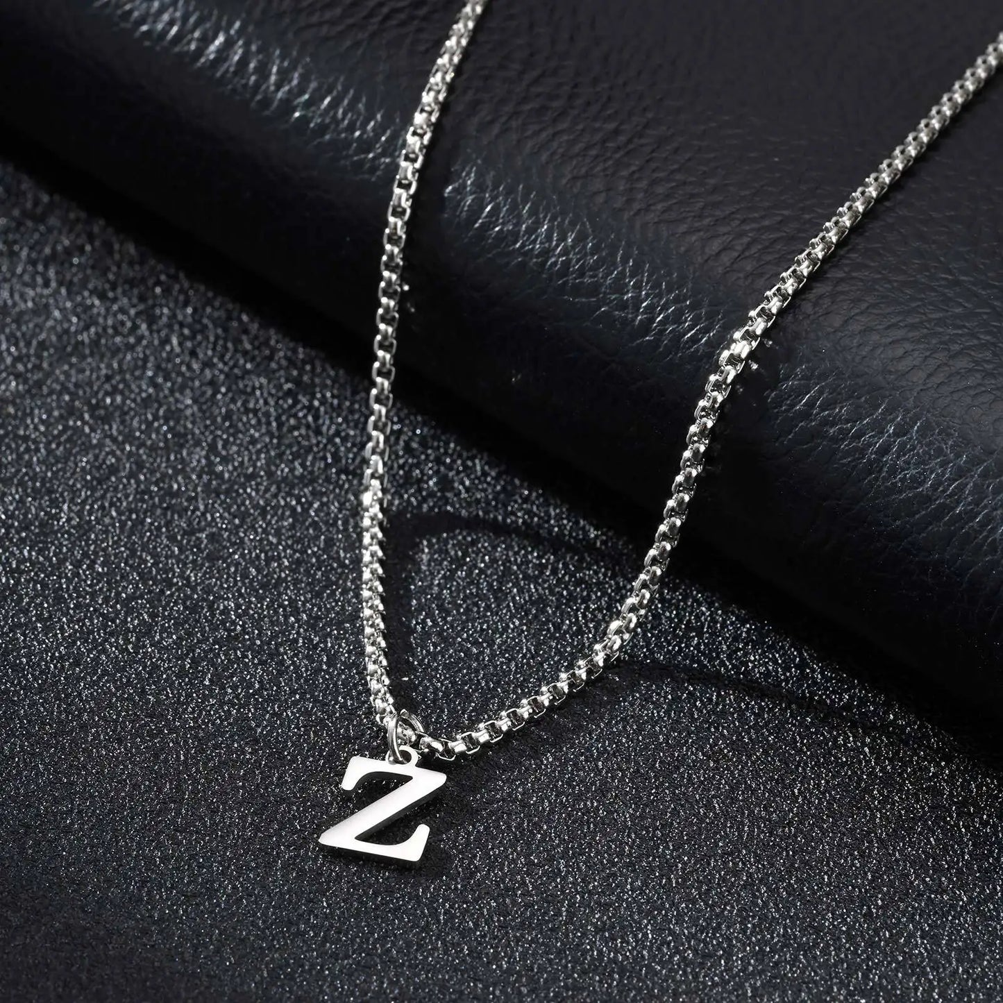 Silver necklace with a 'Z' pendant on a black textured surface