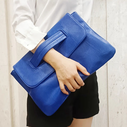 Person holding a blue clutch bag against a neutral background