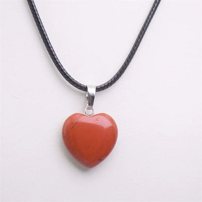 Heart-shaped red pendant on a black cord against a white background