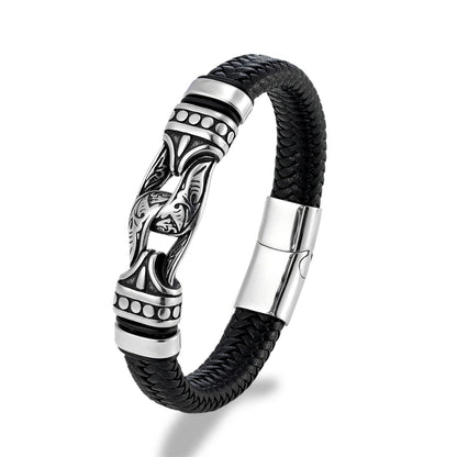 A men's black braided leather bracelet with a polished silver-toned metal centerpiece featuring a stylized face motif and geometric accents, shown on a white background.